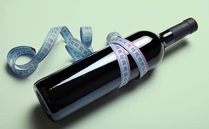 garrafa de vinho envolta de uma fita métrica